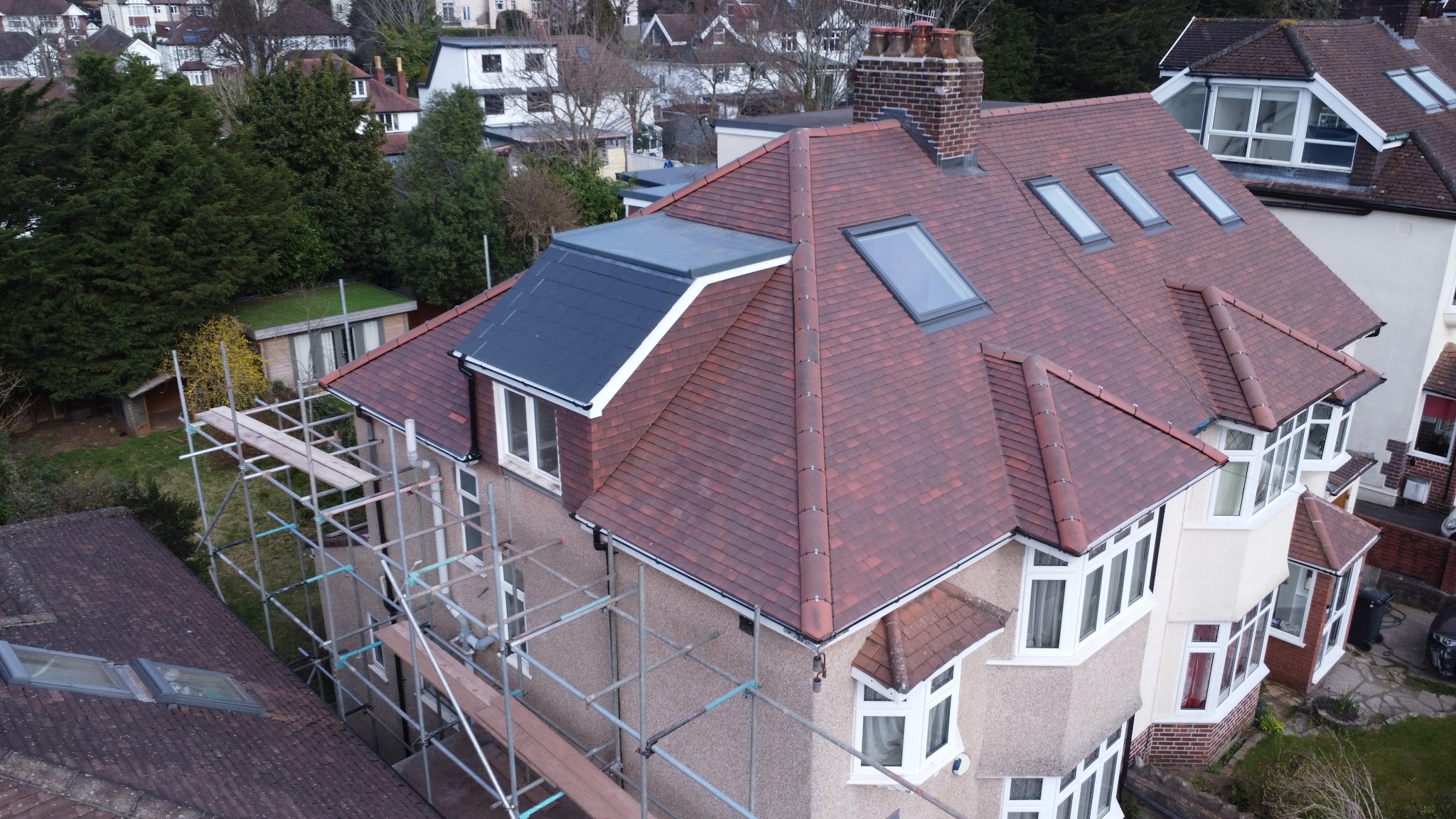 Drone view of a semi-detached house re-roofed in red plain tiles, scaffold still up
