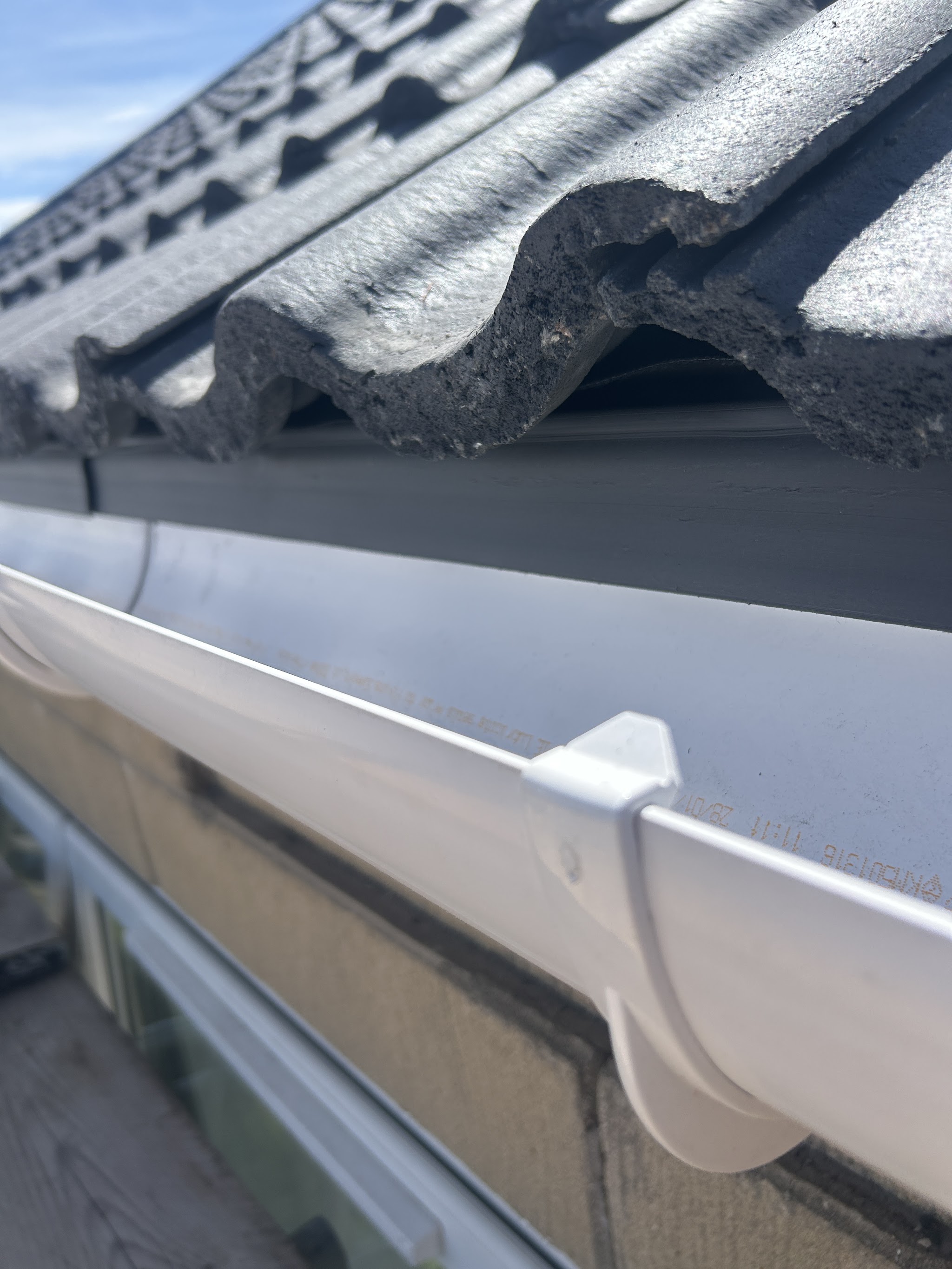 New white guttering fitted under the edge of a grey tiled roof