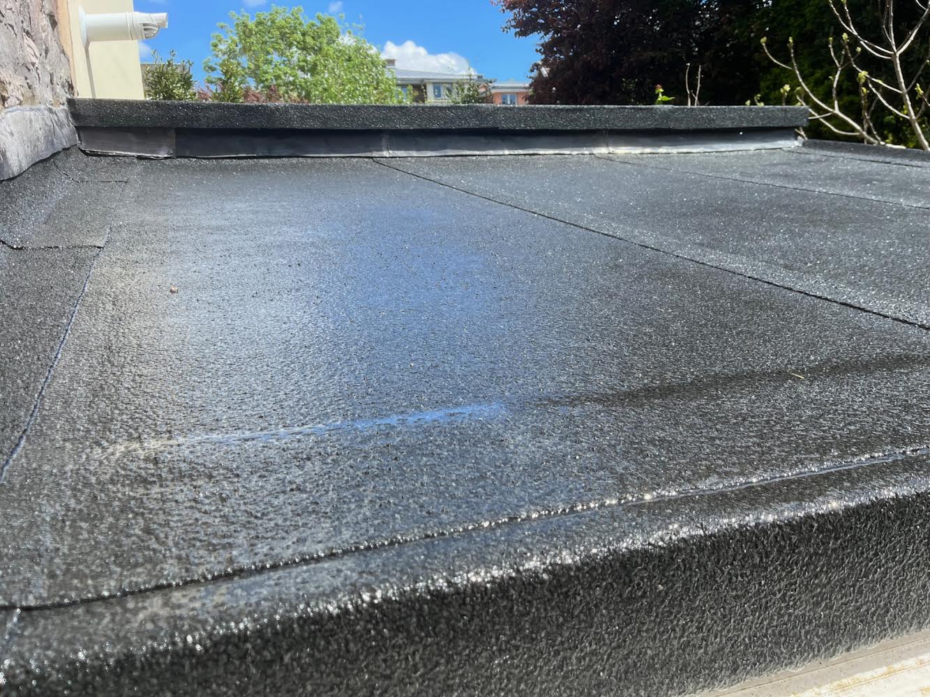 A finished flat roof with a dressed upstand along the wall